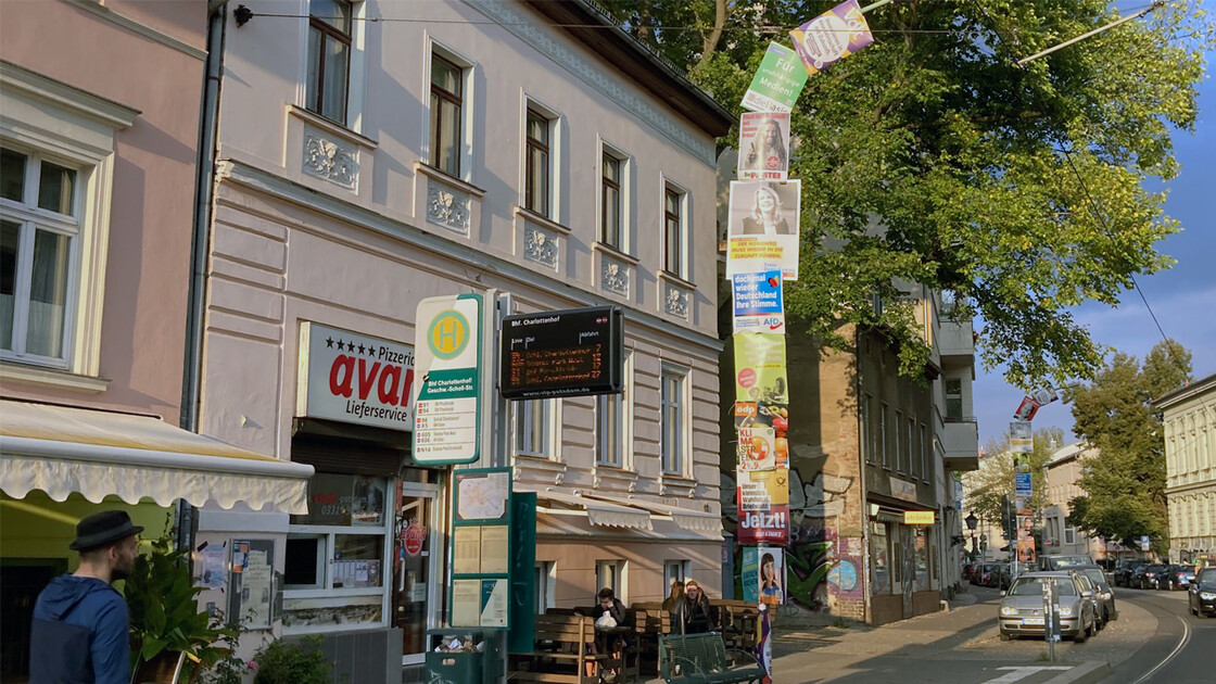 Laternenpfahl an einer Straßenbahnhaltestelle, komplett einschließlich der Biegung über der Straße mit Plakaten eingehüllt.