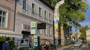 Laternenpfahl an einer Straßenbahnhaltestelle, komplett einschließlich der Biegung über der Straße mit Plakaten eingehüllt.
