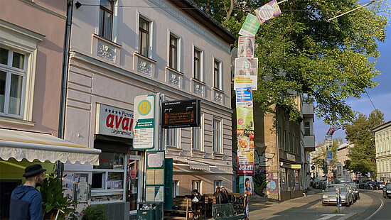 Laternenpfahl an einer Straßenbahnhaltestelle, komplett einschließlich der Biegung über der Straße mit Plakaten eingehüllt.